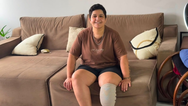 Aline Araújo de Oliveira sentada no sofá sorrindo