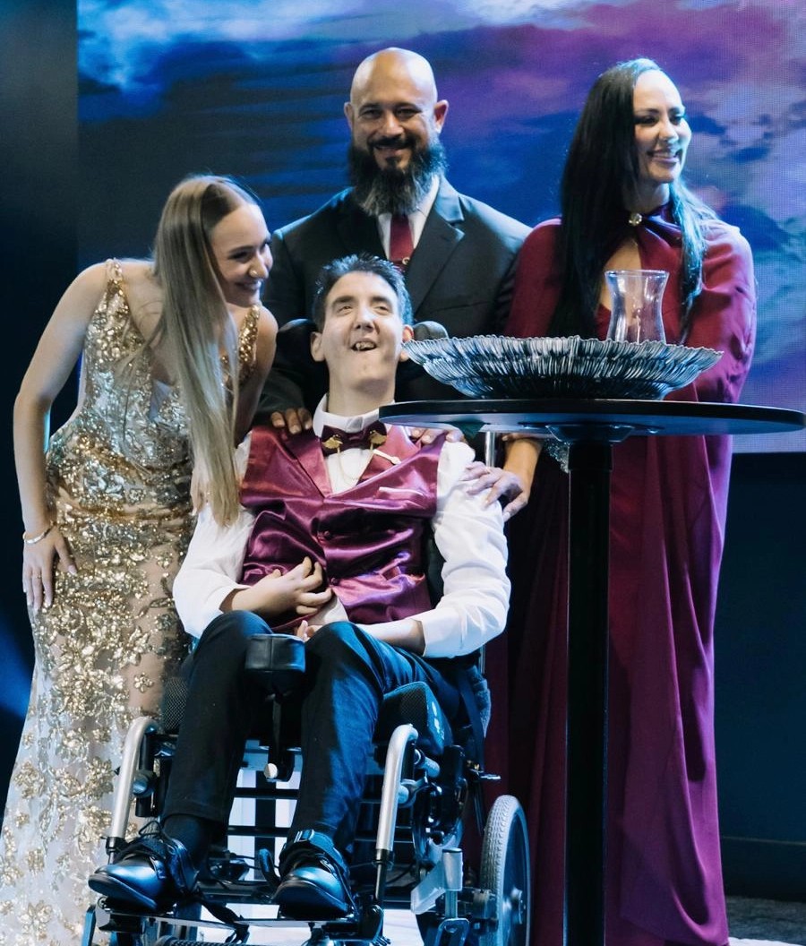 Yan Pereira aparece ao centro, acompanhado pela irmã, Mel, pelo pai, Leandro, e pela mãe, Jô Pereira, durante a cerimônia de lançamento de YAN – Da Dor ao Propósito. O registro mostra a família reunida no palco durante o evento.